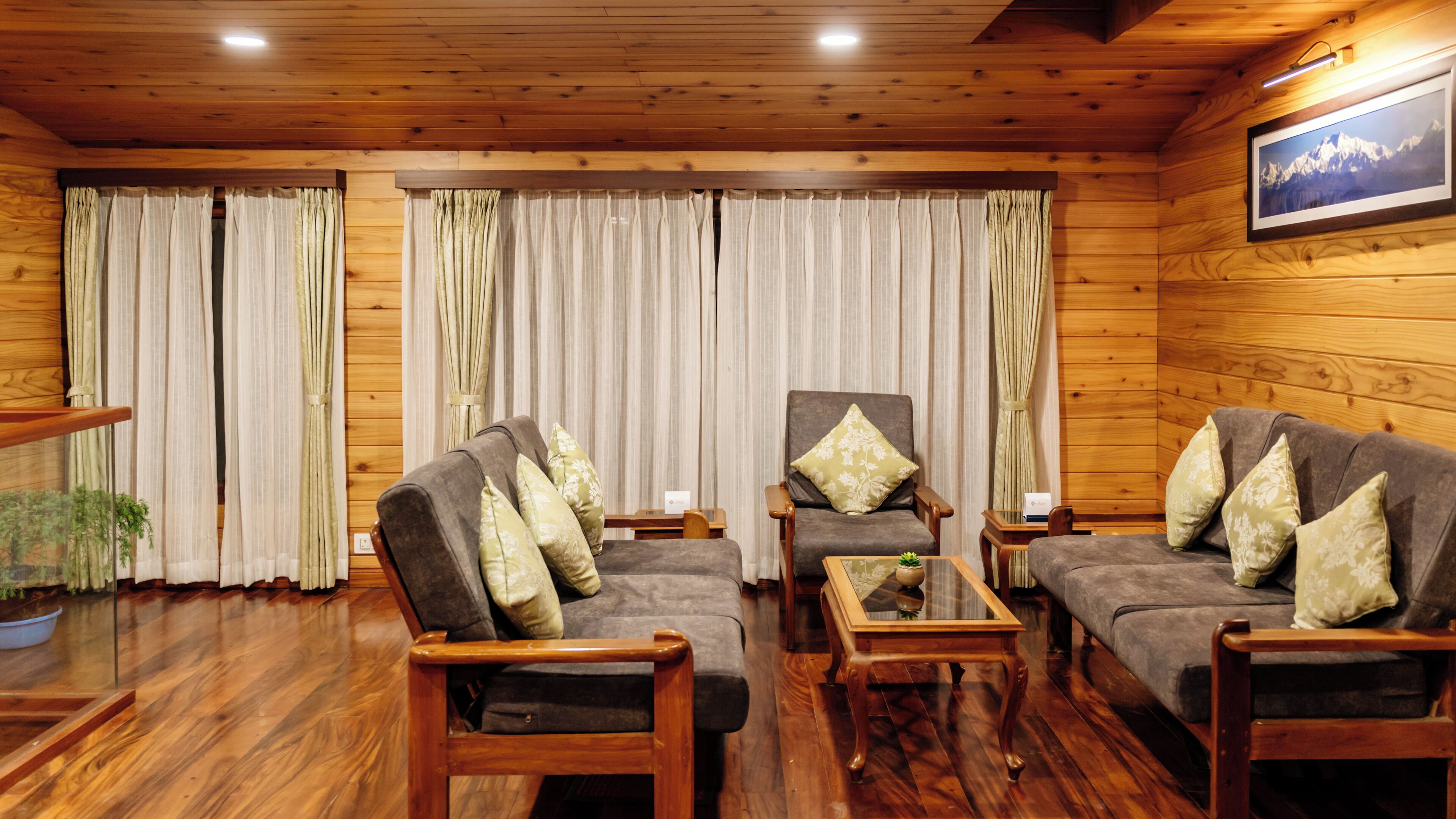 Una habitación acogedora con paredes y suelos de madera, que incluye dos sofás, una silla y una pequeña mesa.