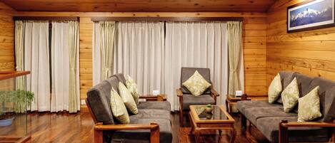 Una habitación acogedora con paredes y suelos de madera, que incluye dos sofás, una silla y una pequeña mesa.
