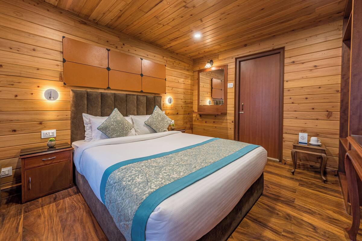 Een slaapkamer met houten lambrisering, een bed, nachtkastjes, een spiegel en een deur.