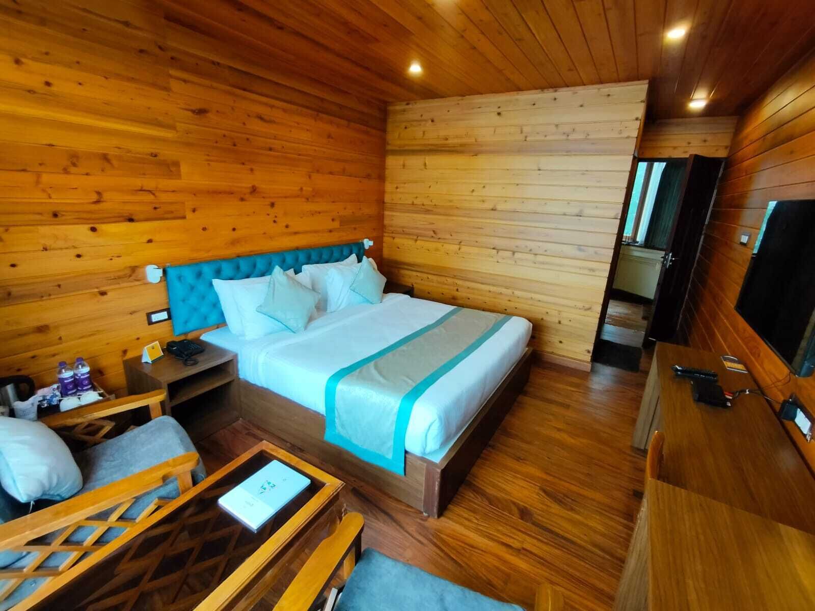 Una habitación de cabaña de madera con una cama, un escritorio, una silla y un televisor.