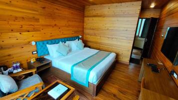 Una habitación de cabaña de madera con una cama, un escritorio, una silla y un televisor.