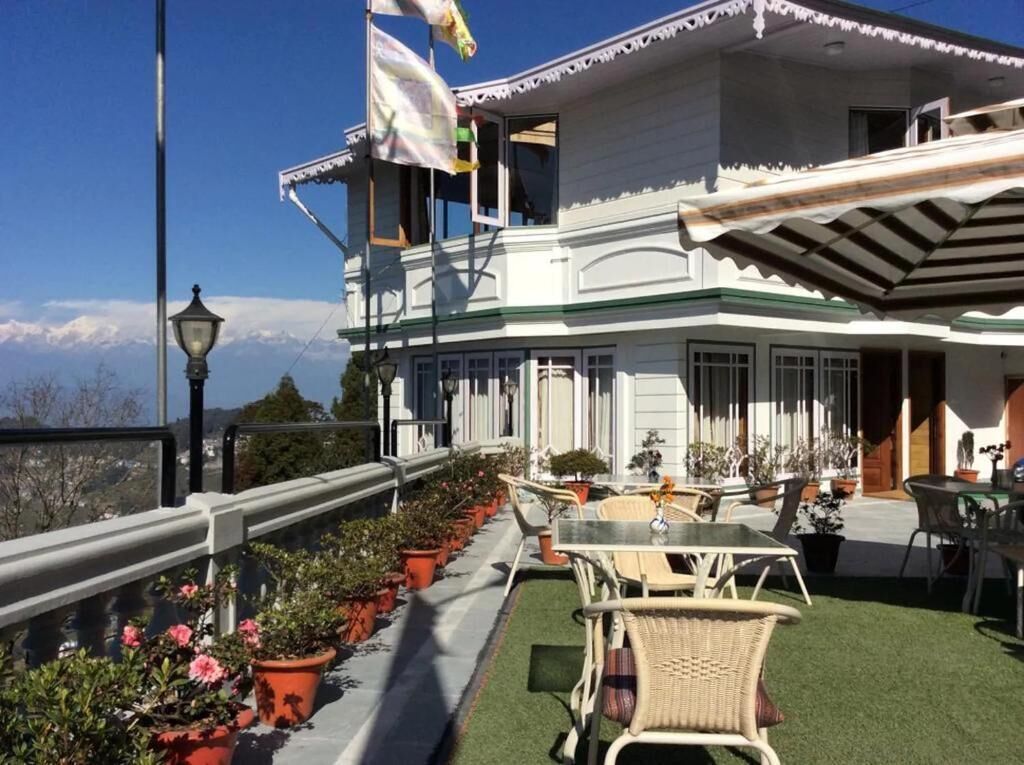 Un bâtiment à deux étages doté d’un balcon, de plantes en pot, de mobilier d’extérieur et offrant une vue sur les montagnes.