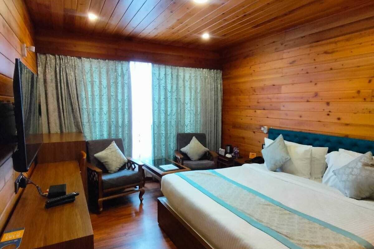Een kamer met houten lambrisering, een bed, een bureau, een stoel en een televisie.