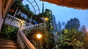 A staircase with a balustrade, surrounded by lush greenery and a glass structure with plants. - Udaan Dekeling Resort Darjeeling (Darjeeling)