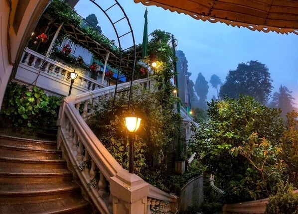 A staircase with a balustrade, surrounded by lush greenery and a glass structure with plants. - Udaan Dekeling Resort Darjeeling (Darjeeling)