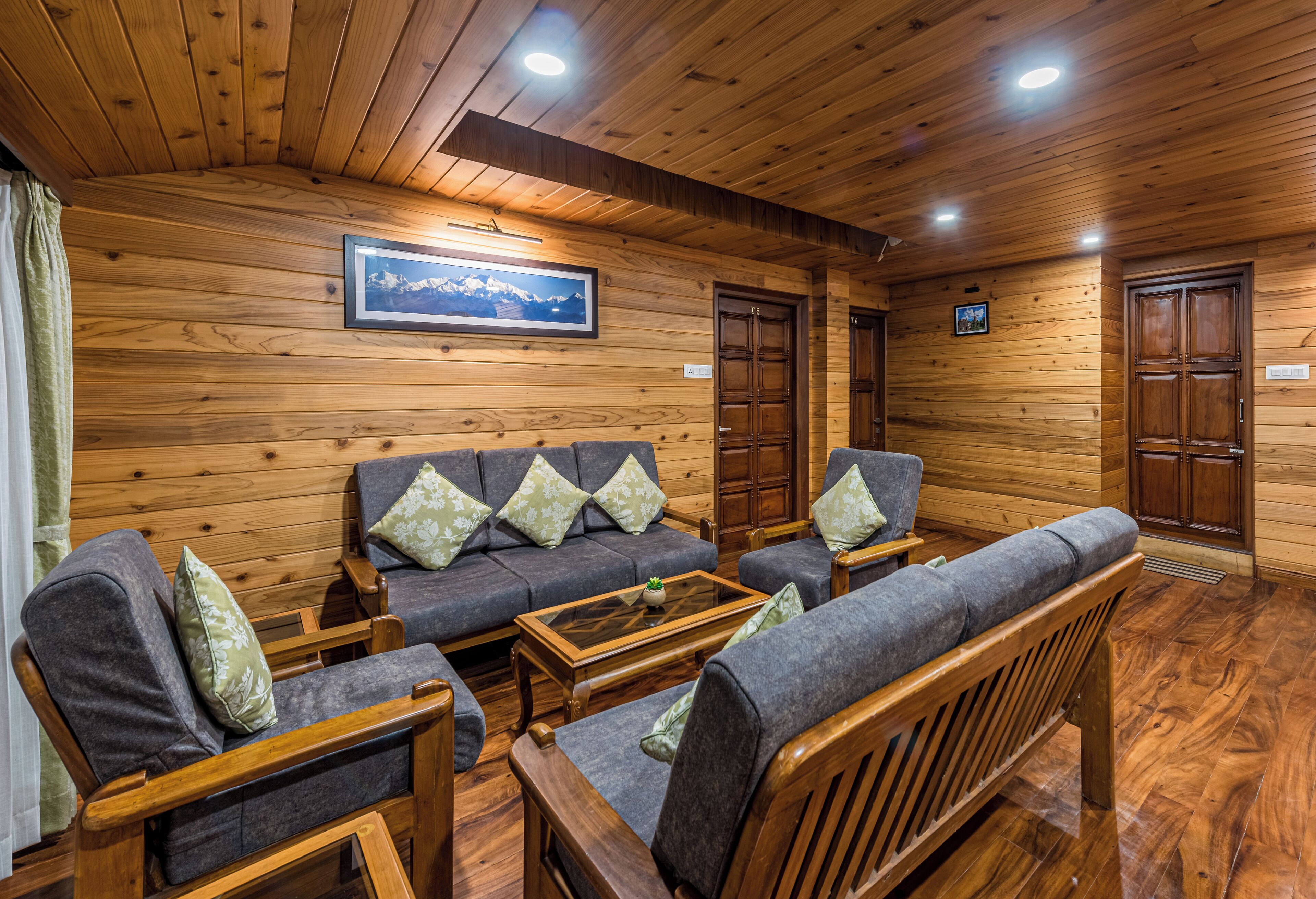 Interior acolhedor de uma cabana de madeira, com sofá, paredes de madeira e um quadro pendurado na parede.