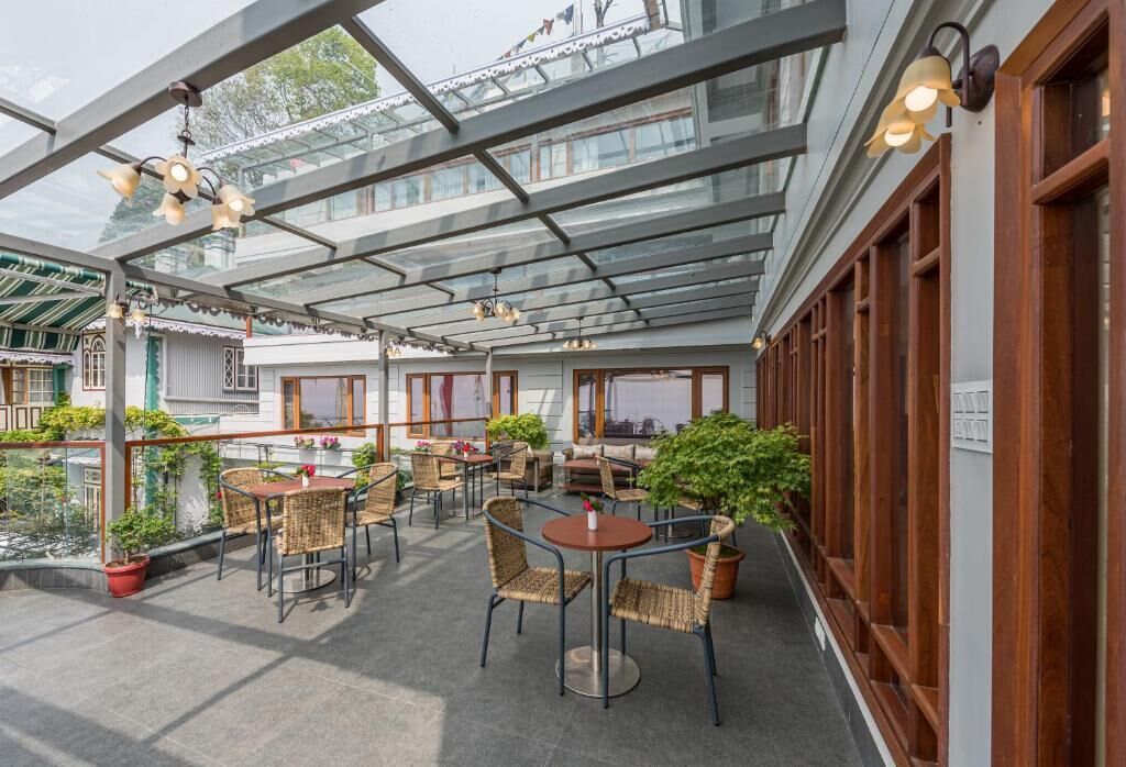 A covered outdoor patio with wicker furniture, potted plants, and a glass ceiling.