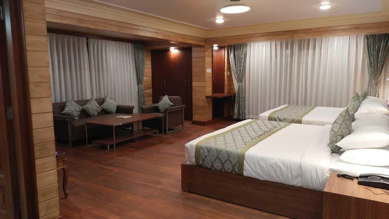 Habitación de hotel con dos camas, un sofá, un escritorio y una mesita.