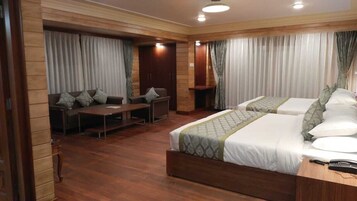 Habitación de hotel con dos camas, un sofá, un escritorio y una mesita.