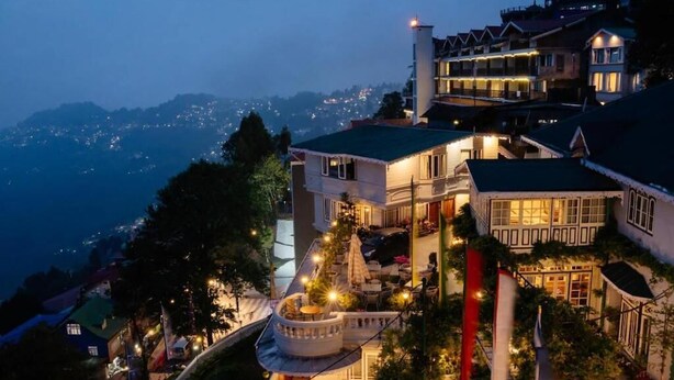 A multi-story hotel with a balcony and outdoor seating area, surrounded by trees and overlooking a mountainous landscape. - Udaan Dekeling Resort Darjeeling (Darjeeling)