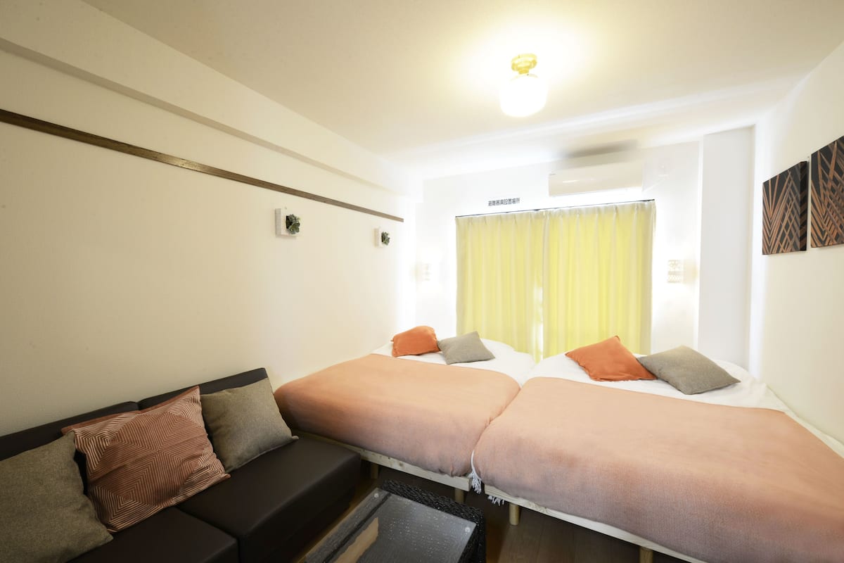 A hotel room with two beds, a sofa, and a small table.