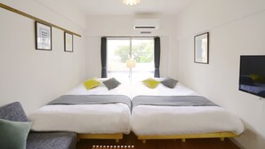 Una habitación con dos camas, un sofá y una ventana con cortinas.