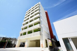 A multi-story building with a white facade and green balconies.