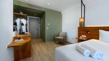 A hotel room with a wooden desk, a chair, a bed with white linens, and a nightstand with a lamp.