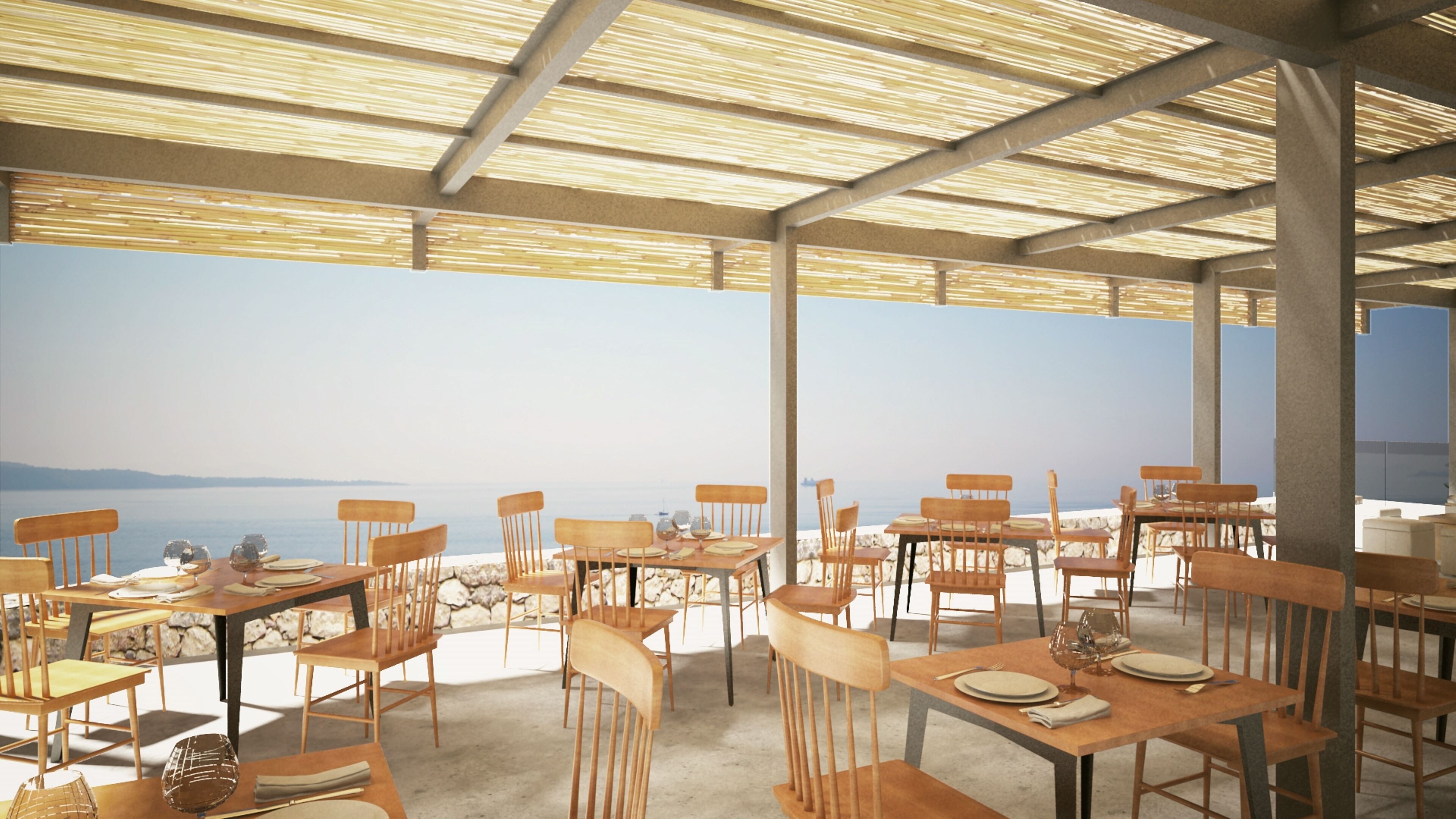 An outdoor dining area with tables and chairs, overlooking a body of water.