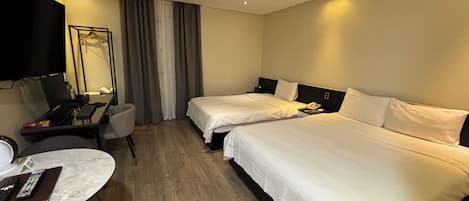 Habitación de hotel con dos camas, un escritorio con silla, televisor y una mesita con control remoto.