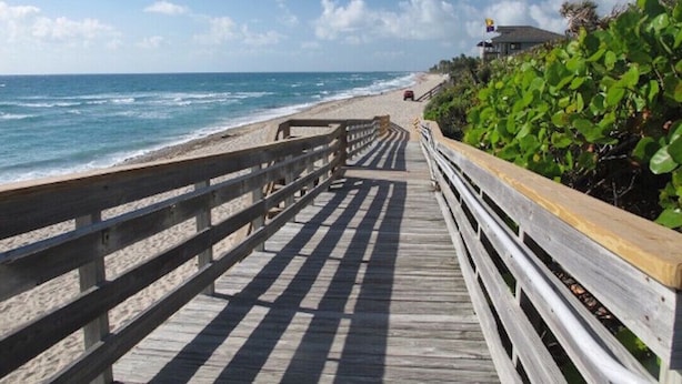 A wooden boardwalk leading to a beach with ocean views.