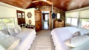 A cabin with two beds, a ceiling fan, a rustic wooden ceiling, and a view of the outdoors.