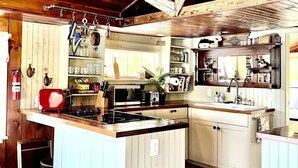 A compact kitchen with wooden cabinets, a central island, and a built-in oven.