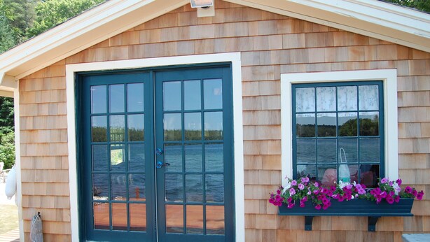 A wooden cabin with a large sliding door and a window with a flower box.