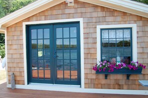 Una cabaña de madera con un amplio ventanal corredero y una ventana adornada con flores.