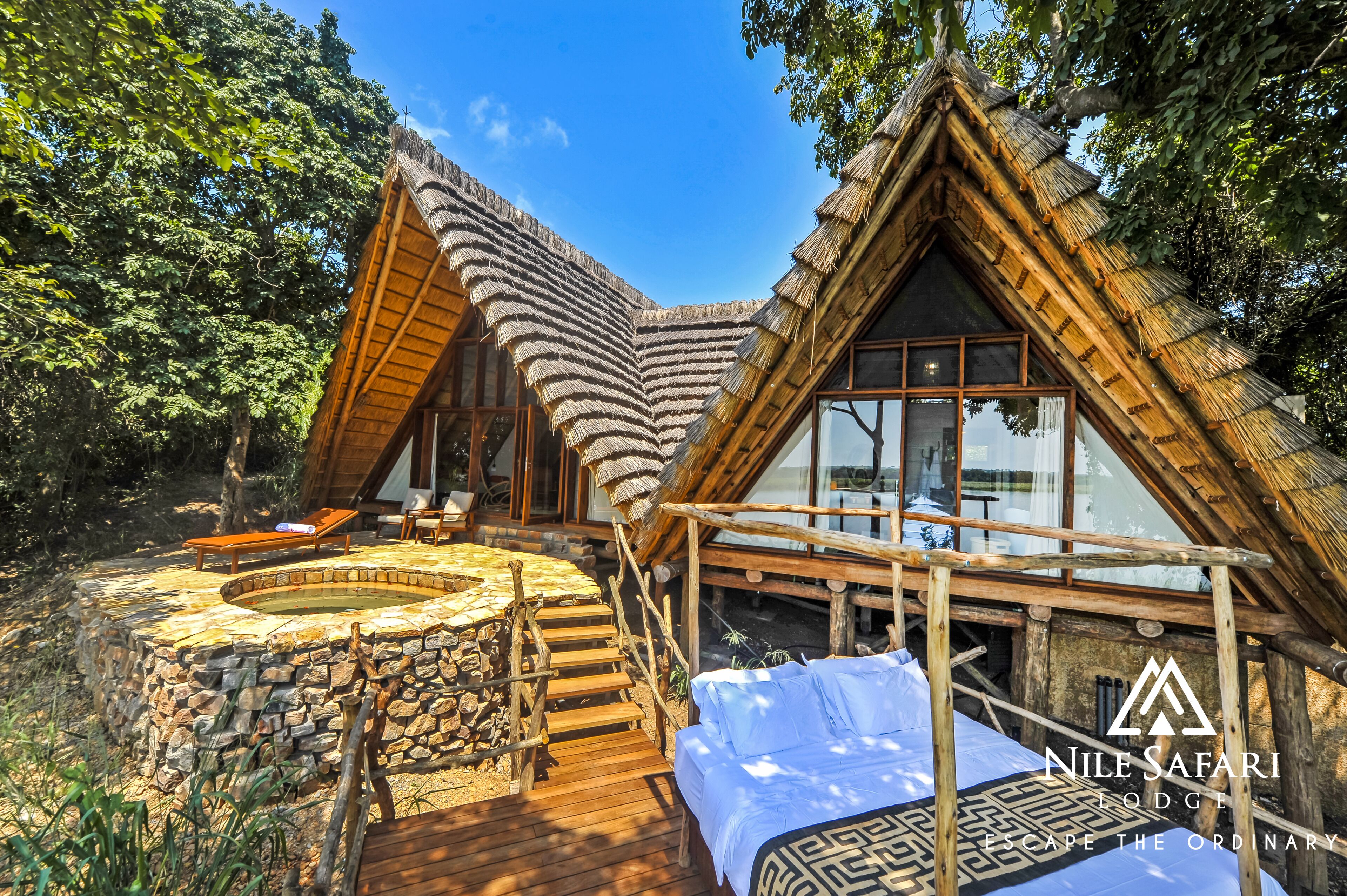 A lodge with a thatched roof, a hot tub, and a wooden deck.