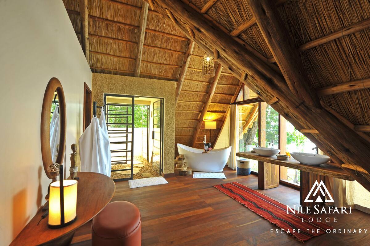 A spacious bathroom with a large bathtub, wooden beams, and a view of the outdoors.