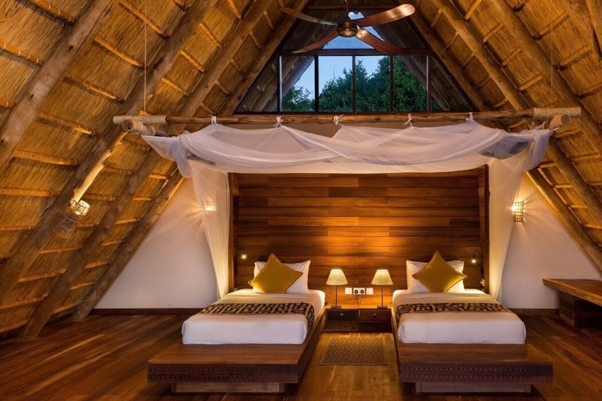 A cozy, rustic bedroom with a wooden ceiling and a large bed with two pillows.