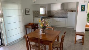 A modern kitchen with white cabinets, a wooden dining table, and a vase of flowers. - River house surrounded by greenery. (San Giacomo)
