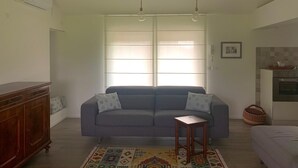 A living room with a grey sofa, a wooden sideboard, a small wooden table, and a patterned rug. - River house surrounded by greenery. (San Giacomo)