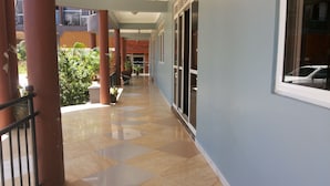 A corridor with a tiled floor, a railing, and potted plants. - Pauline Hotel (Lira)