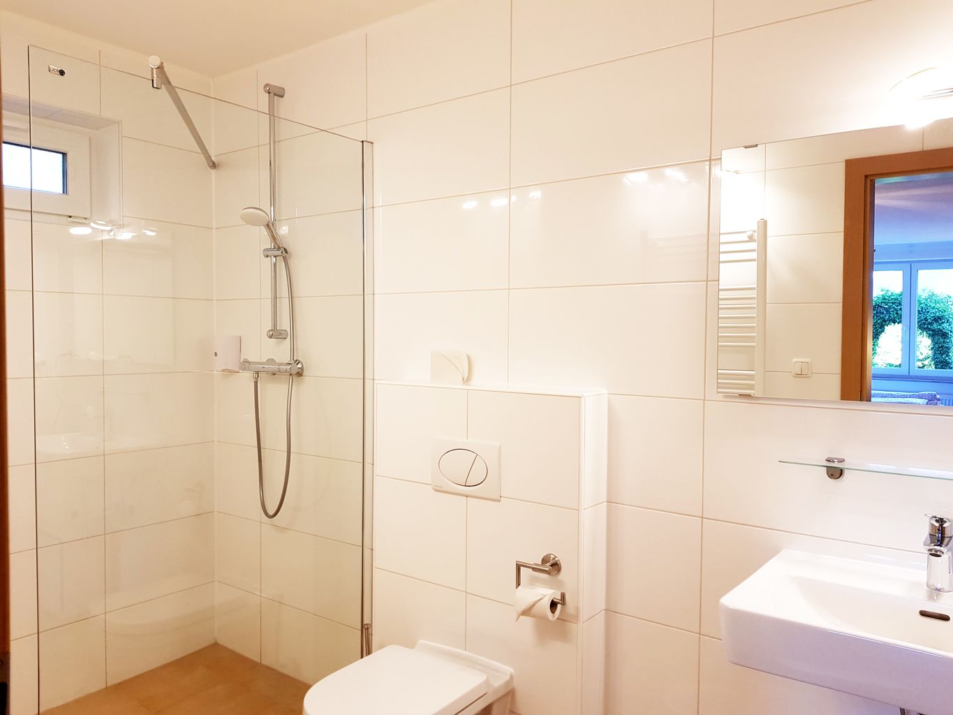 A modern bathroom with a shower, toilet, and sink.