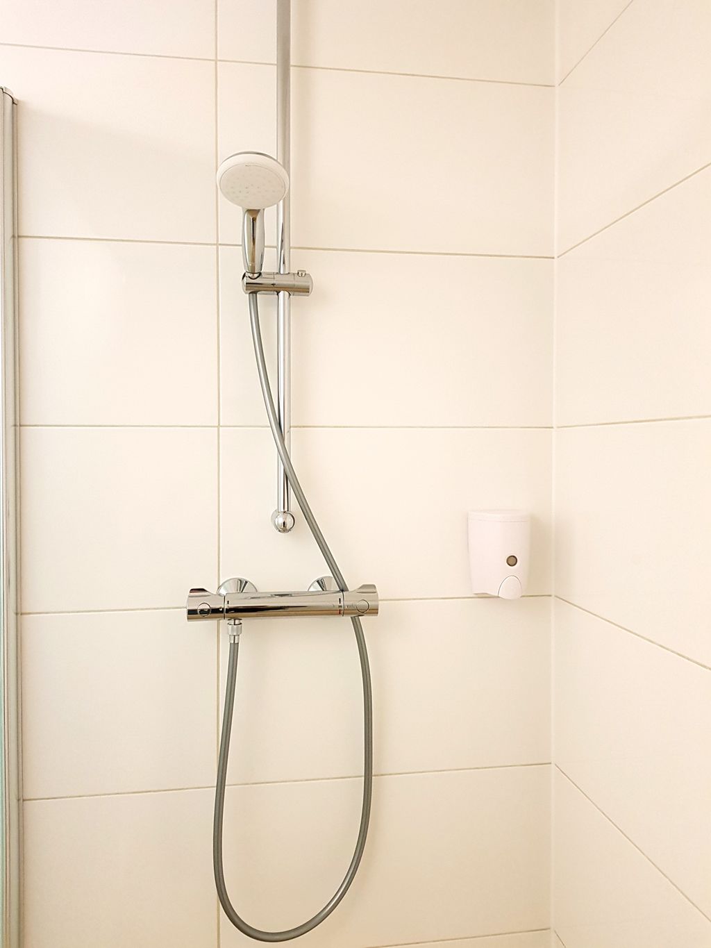 Una ducha con cabezal de ducha manual y manguera.