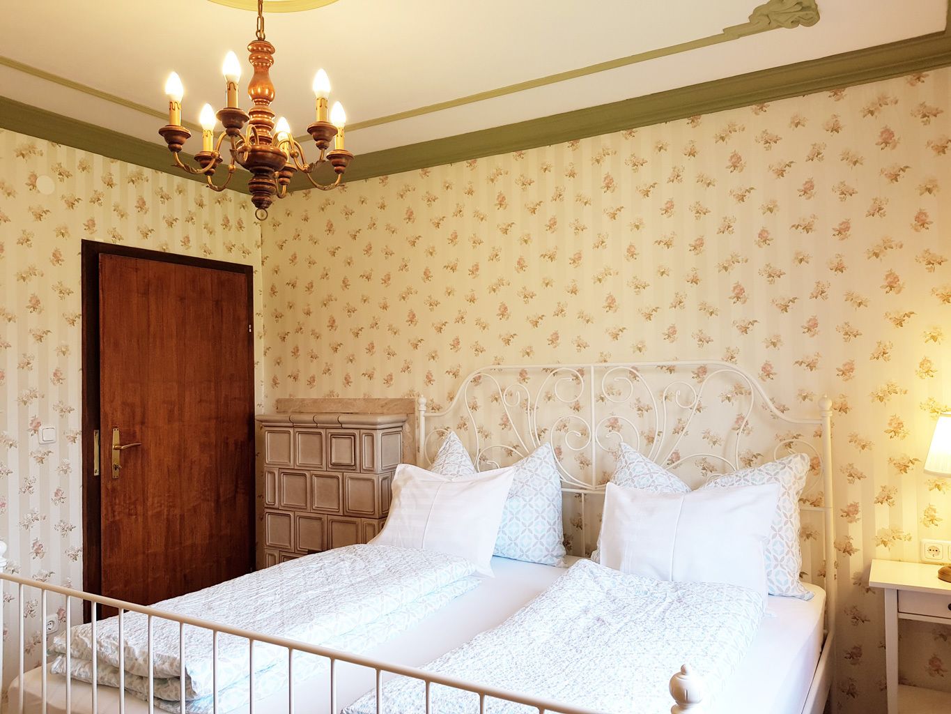 Ein Schlafzimmer mit einem Doppelbett, einem Holzschrank und einer Chandelüster.
