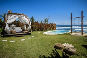 Een privé zwembadgedeelte met een zonnedekbed, een houten terras en uitzicht op zee.
