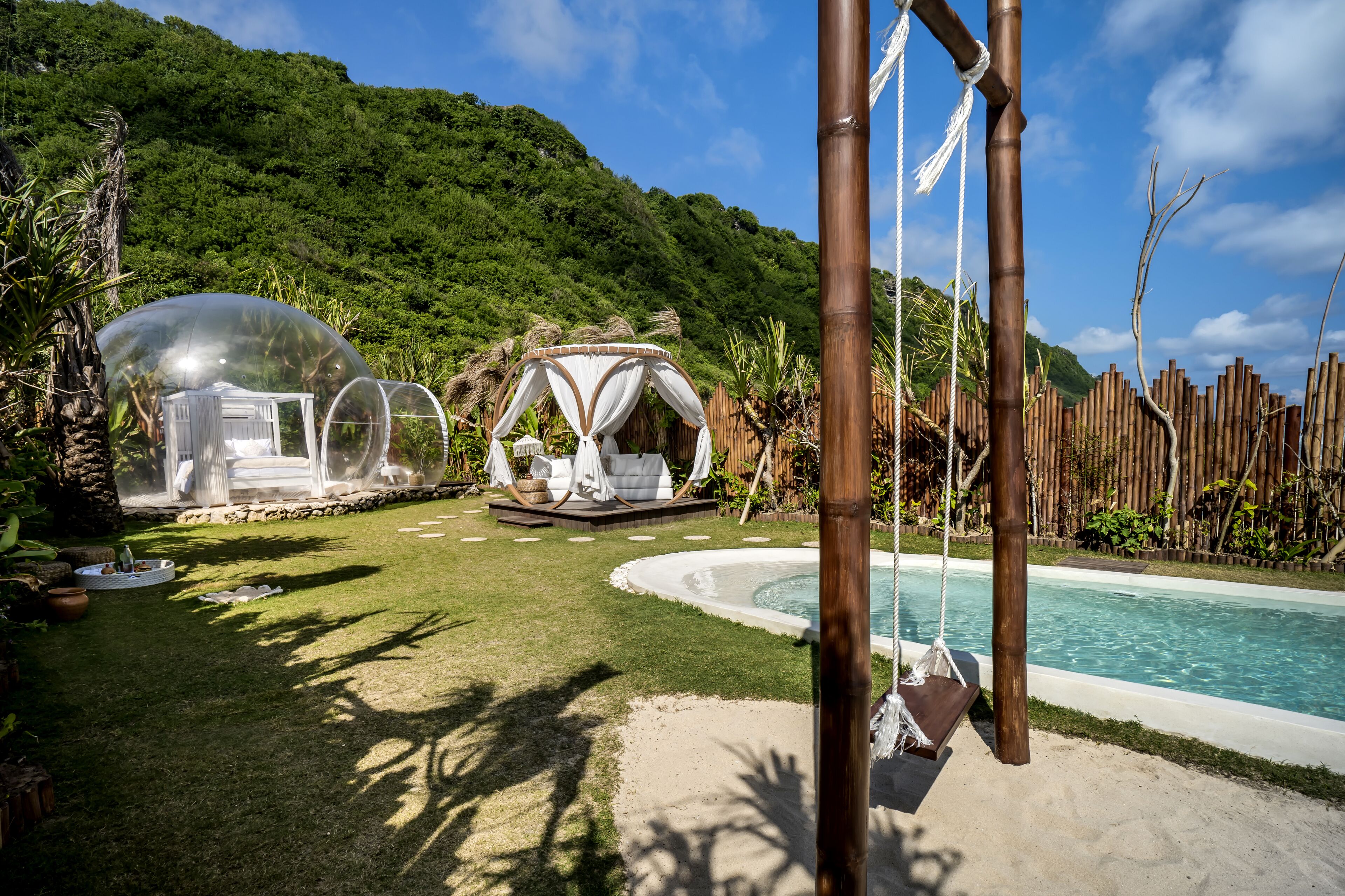 A pool area with transparent domes, a swing, and a wooden fence.