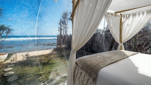 Un lit avec vue sur une plage et des falaises.