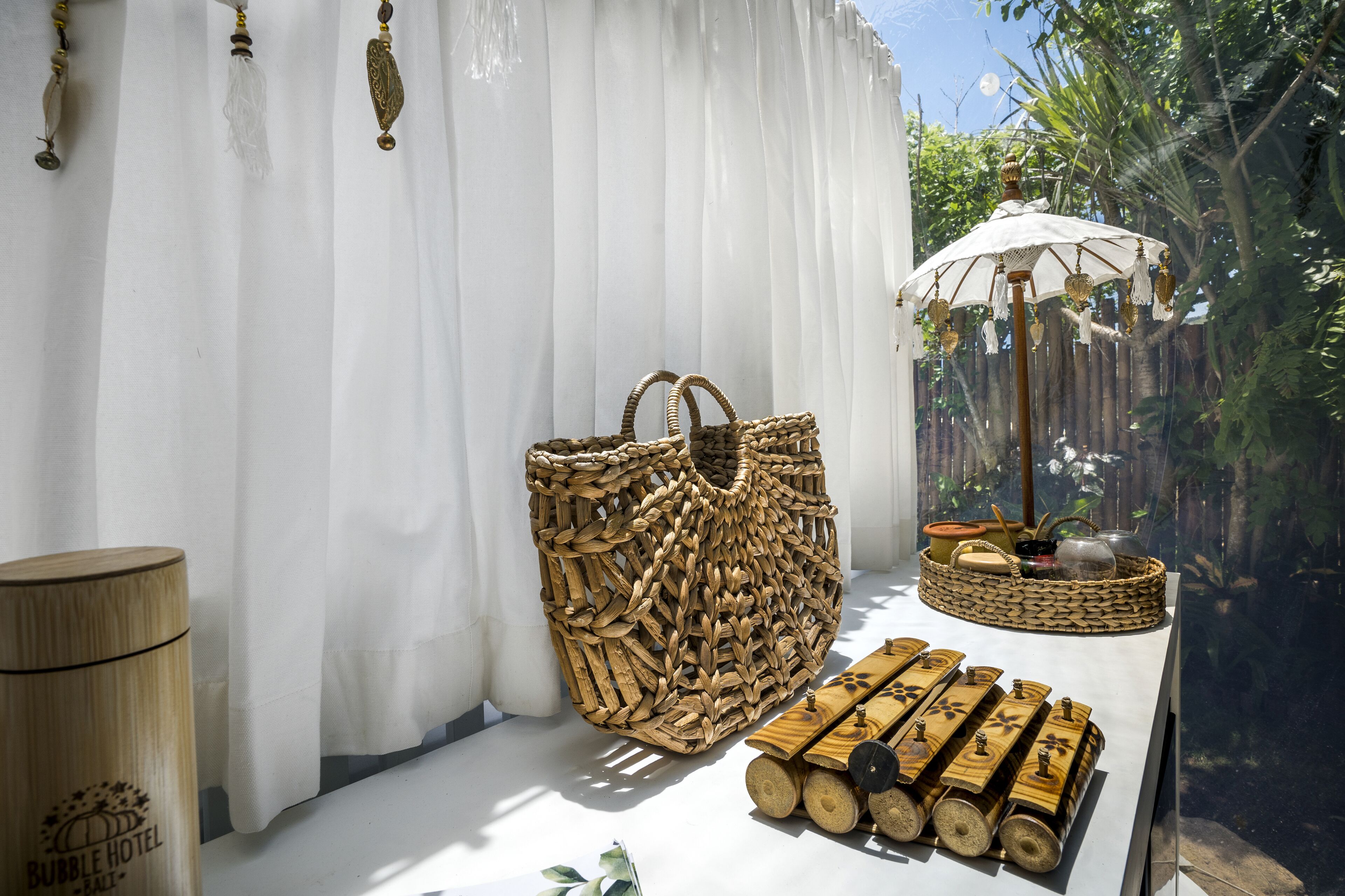 A wicker basket, a wooden stool, and a small table with a woven basket on a white surface.