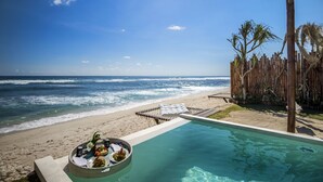 Une vue sur la piscine, avec une plage et l’océan en arrière-plan.