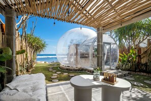 Una estructura de cúpula transparente, un área de descanso con asientos blancos acolchados y una mesa redonda con un tablero de juego.