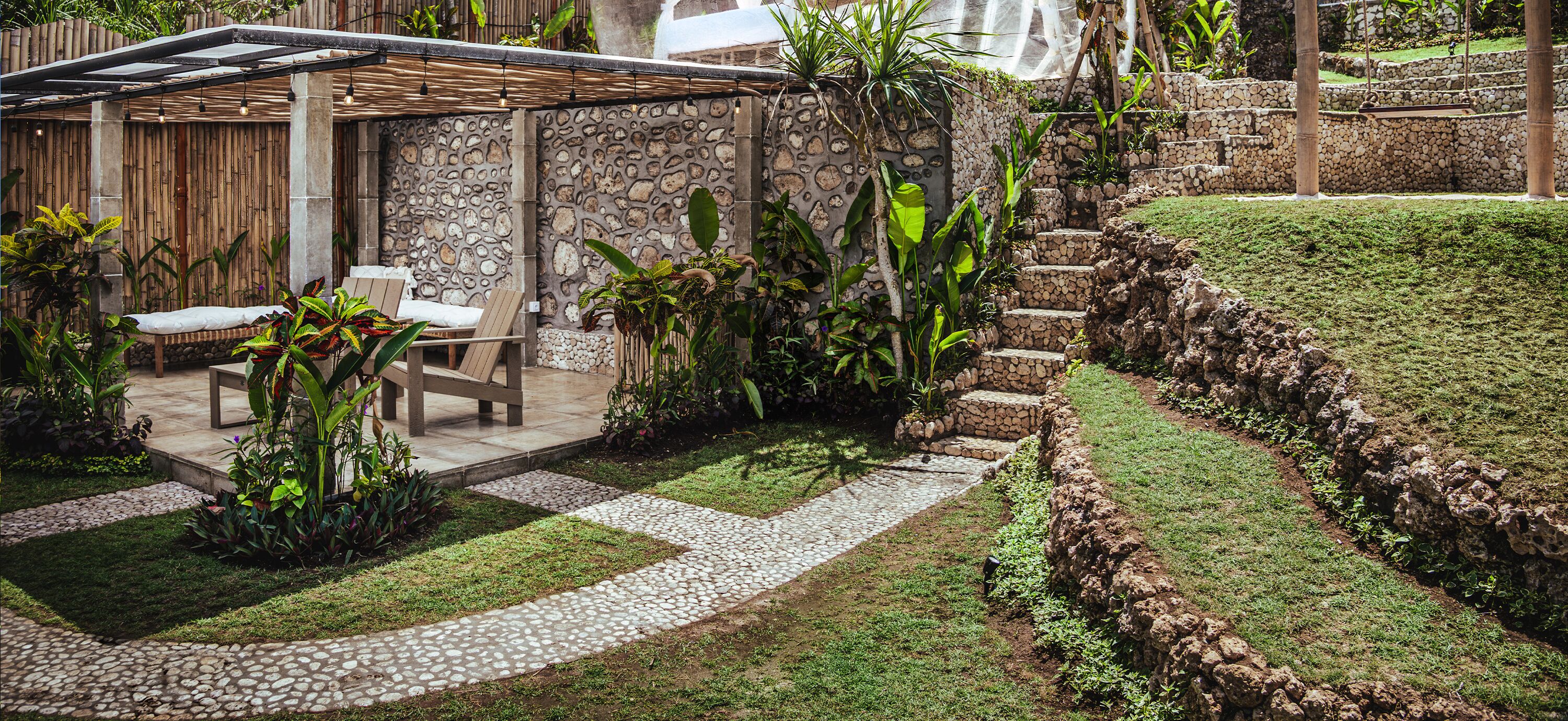 A patio area with stone walls, a wooden pergola, and outdoor seating.