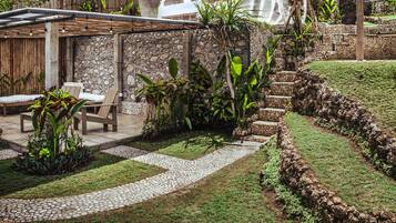 A patio area with stone walls, a wooden pergola, and outdoor seating.