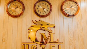 Tres relojes de pared y el logotipo de un hotel sobre una pared de madera.