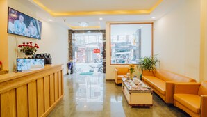 Una zona de recepción con un mostrador de madera, un televisor montado en la pared, un sofá y una mesa de centro.