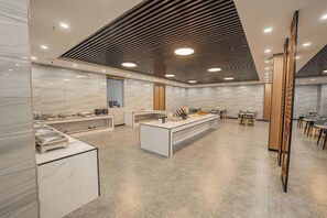 Une cuisine moderne et bien éclairée, dotée de plans de travail en marbre, d’un îlot central et d’un plafond en bois au design original.