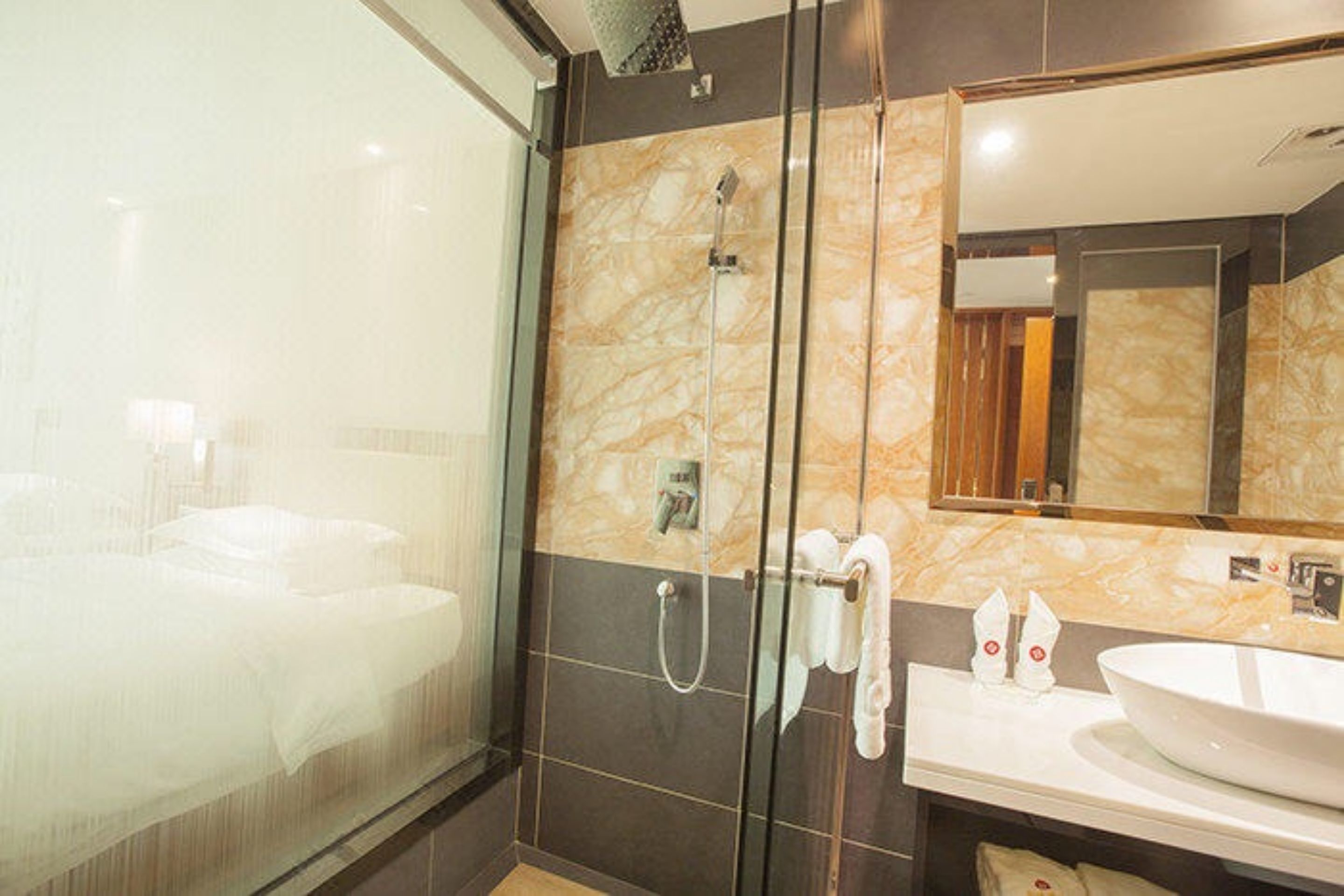 Ein modernes Badezimmer mit einer Duschkabine aus Glas, einem großen Spiegel und einem weißen Waschbecken.