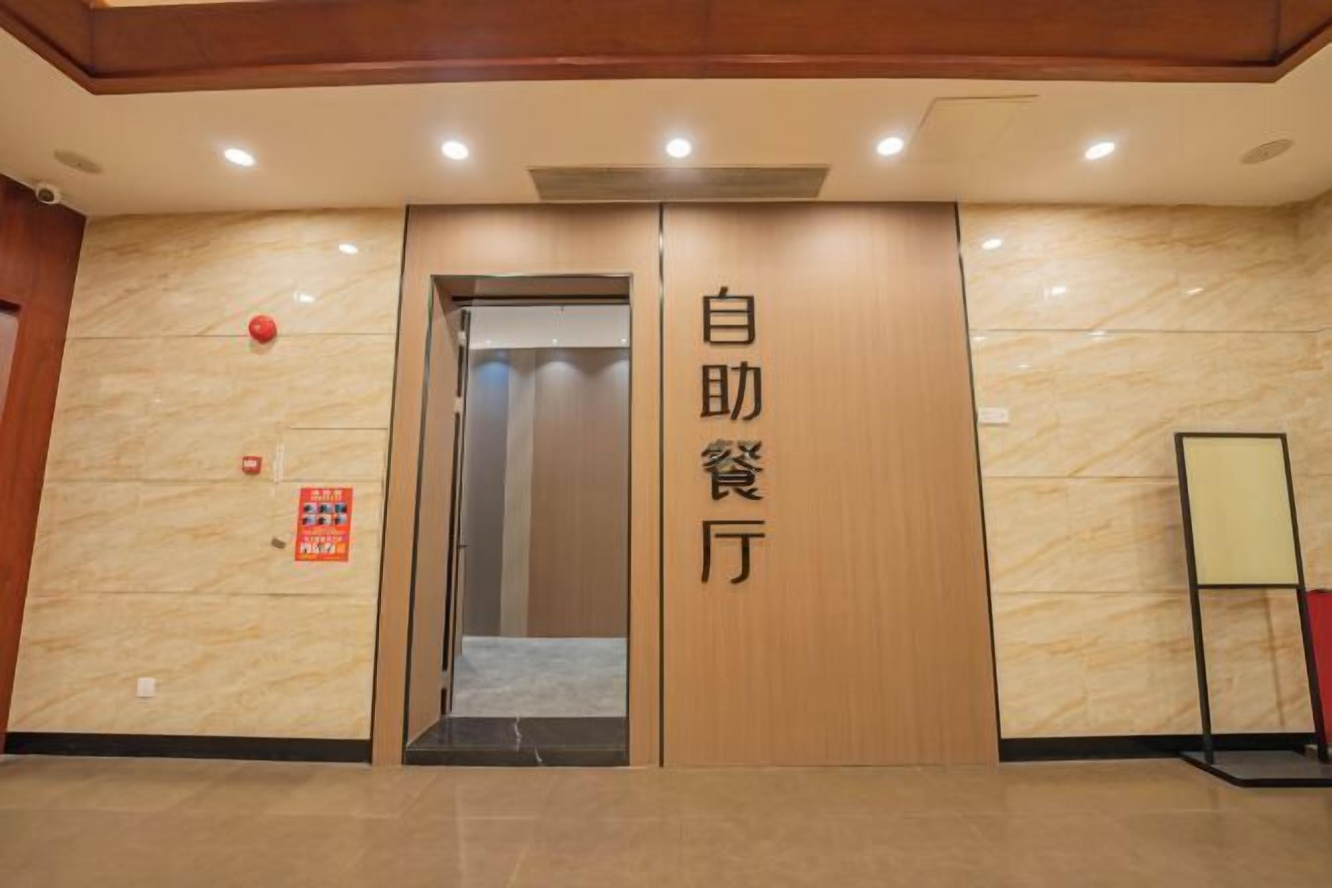 Entrada de un hotel con puerta de madera y un letrero en caracteres chinos.