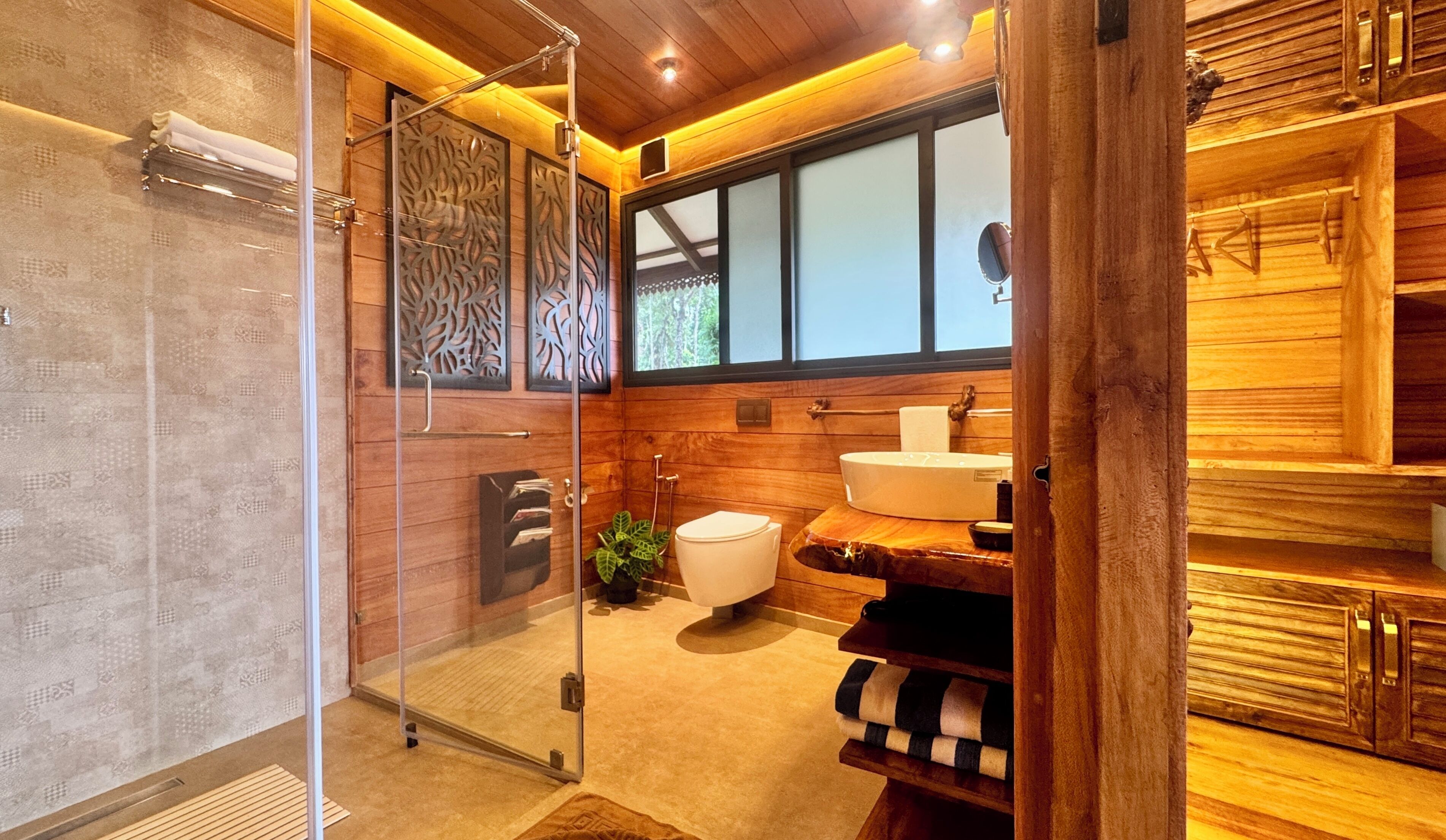 A modern bathroom with a glass shower enclosure, a toilet, a sink, and a wooden vanity.