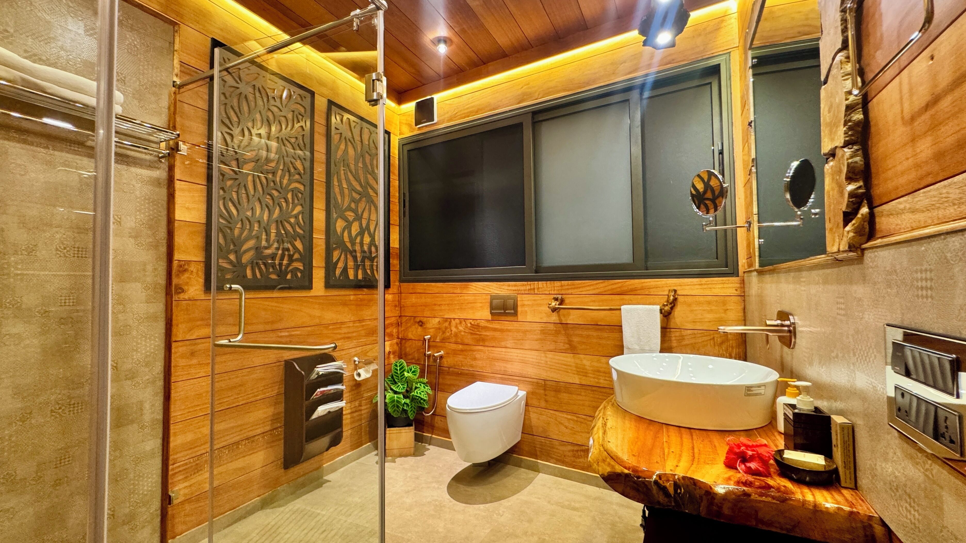 A modern bathroom with a glass shower enclosure, a white toilet, and a large sink with a wooden countertop.