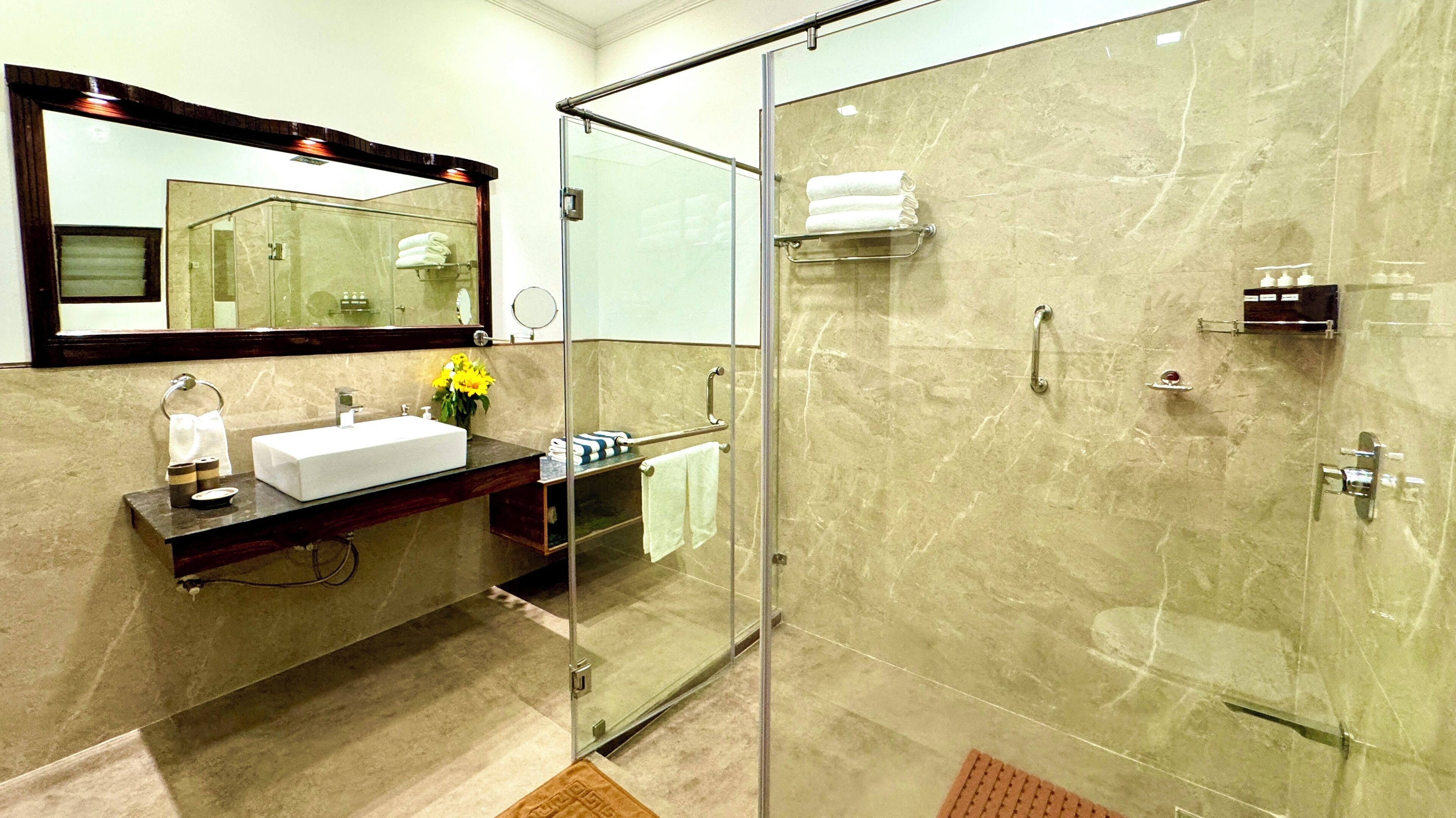 A modern bathroom with a glass-enclosed shower, a vanity with a sink, and a large mirror.